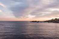 Scenic view of ripple of ocean with rough stoned shore against sky with spindrift clouds in evening
