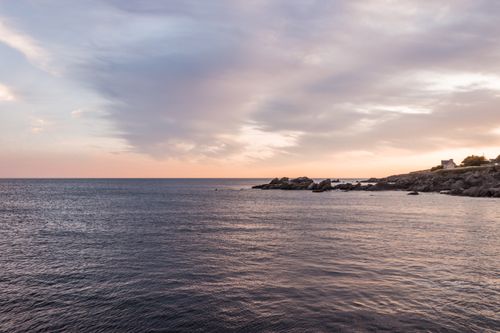 Free Scenic view of ripple of ocean with rough stoned shore against sky with spindrift clouds in evening Stock Photo