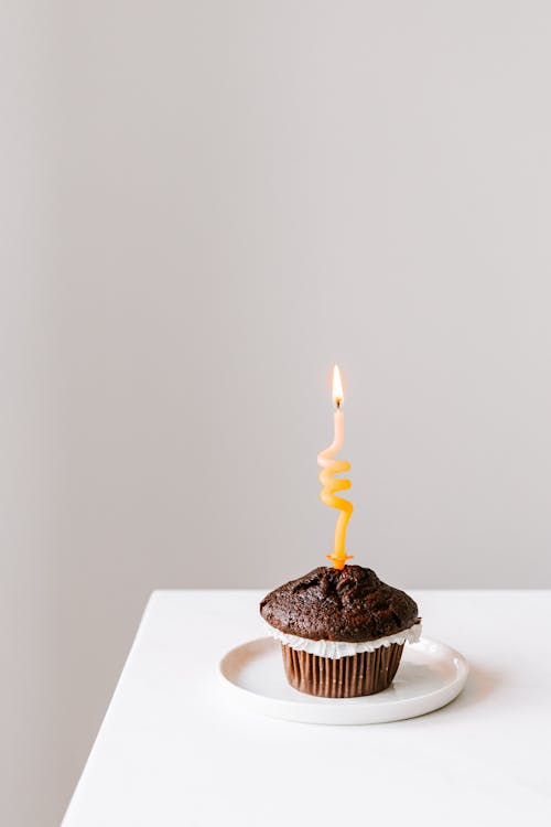 Free Yellow Candle on a Chocolate Cupcake Stock Photo
