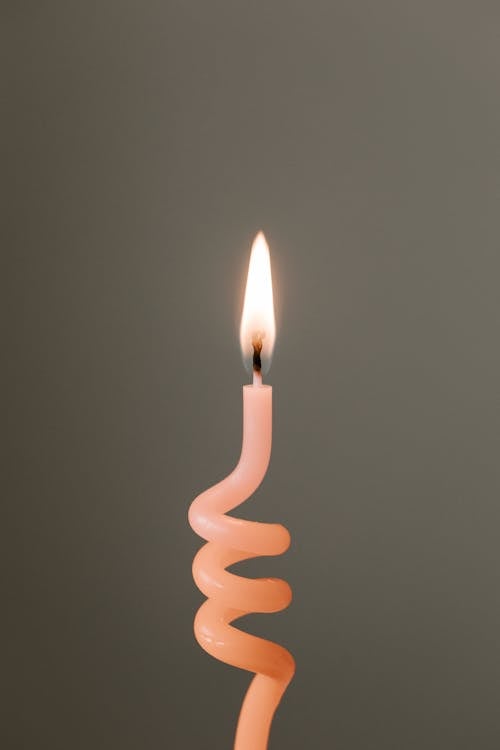 Free Burning pink candle against gray background Stock Photo