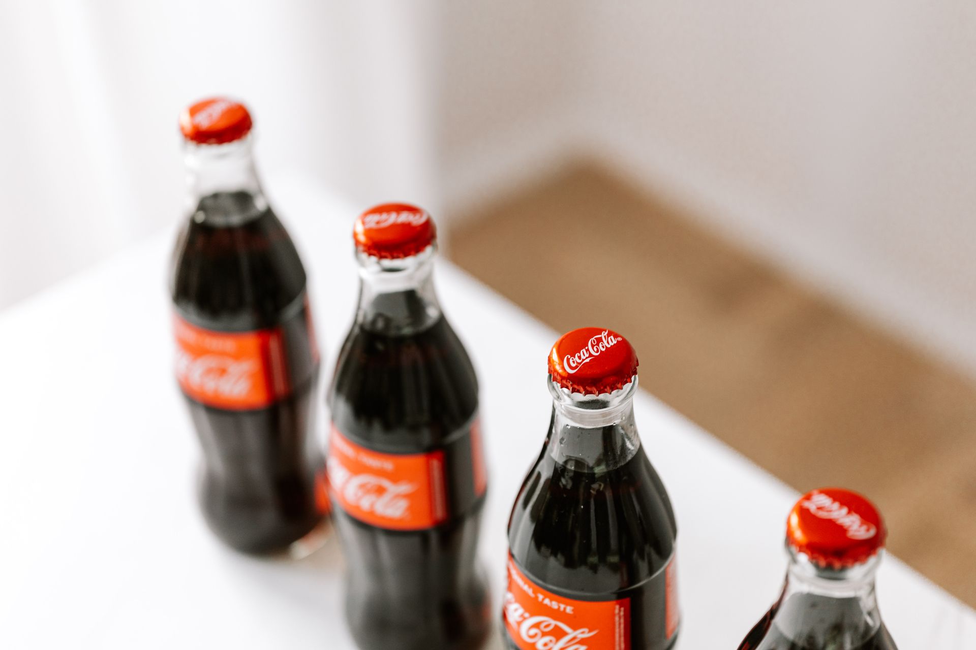 From above of full bottles of coke placed in row on white table