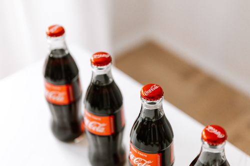 Free From above of full bottles of coke placed in row on white table Stock Photo