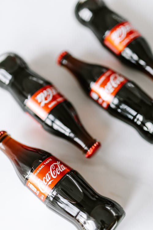 From above of glass bottles of fresh nonalcoholic beverage placed on white surface