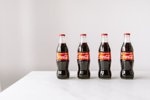 Glass bottles of cola on white table