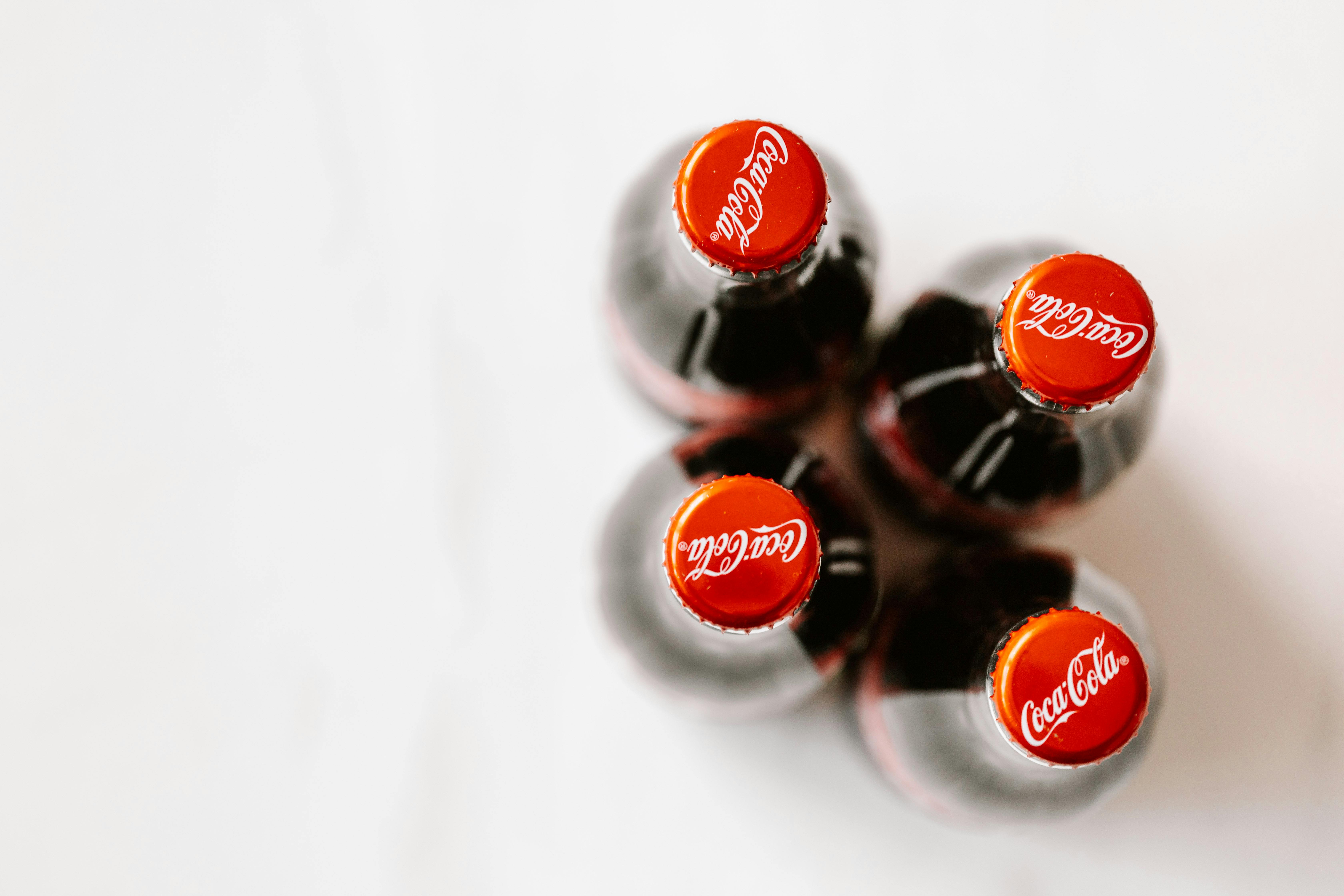 Bottles of Coca Cola placed on white surface Free Stock Photo