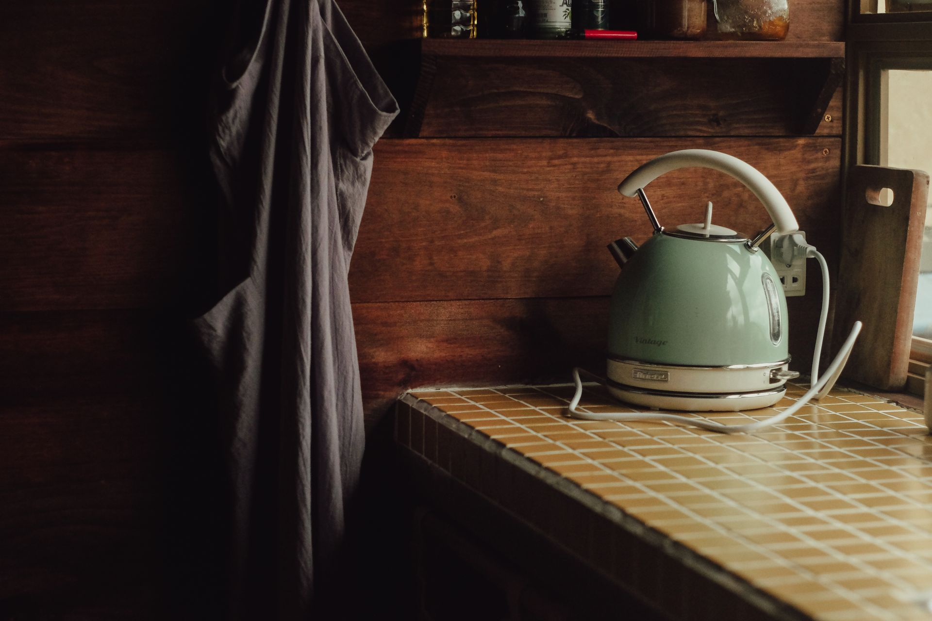 A cozy kitchen scene featuring a vintage teal kettle on a tiled counter with a warm, rustic feel.