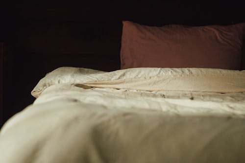 Brown Pillow on White Bed Linen