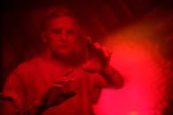 霓虹灯下，一名男子的肖像模糊，重点是他那双富有表情的纹身双手