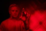 在戏剧性的红色灯光下，一个模糊的男子用食指指着