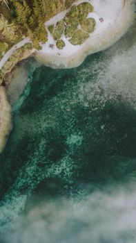 Serene aerial view of a forested shoreline meeting clear turquoise waters.