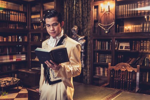 Intelligent Asian man reading book in home library
