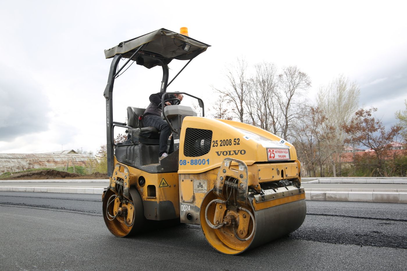 Road roller performing tar surfacing