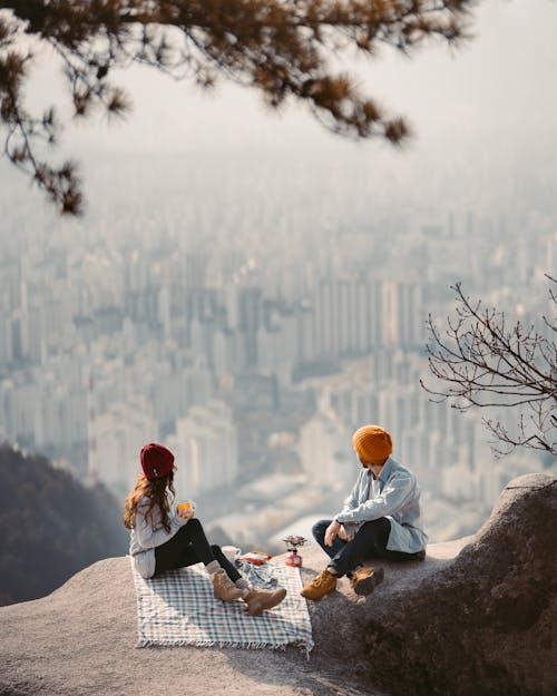 Free A Couple Sitting on Cliff Having a Picnic Stock Photo