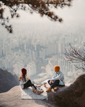 一对夫妇在风景优美的悬崖上野餐，欣赏着首尔天际线的壮丽景色