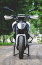 Motorcycle parked on city street near green trees
