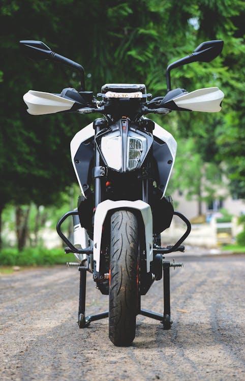 Free Motorcycle parked on city street near green trees Stock Photo