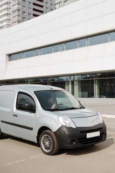 一名男子在一辆停在现代建筑前的面包车里使用智能手机