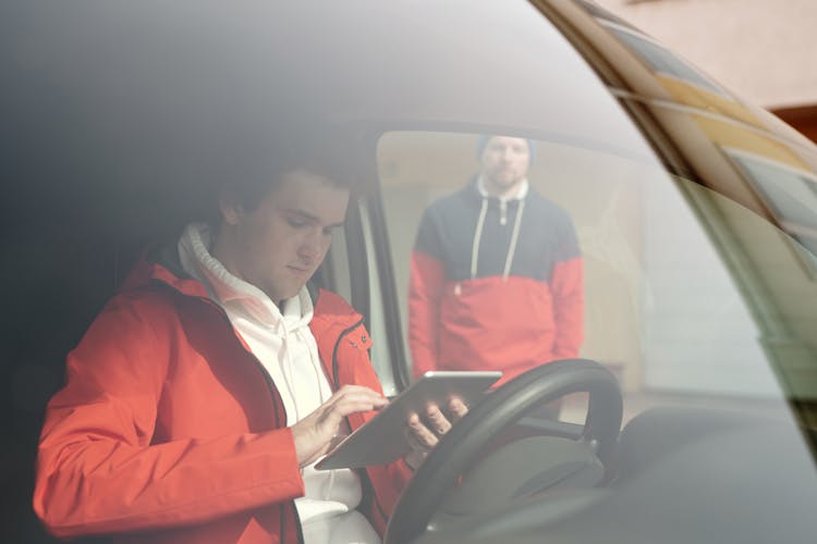 Man Sitting On The Car While Using His Tablet Computer 