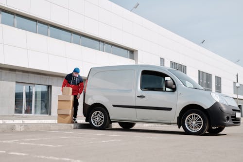 Free Delivery Man With Boxes next to a White Van Stock Photo