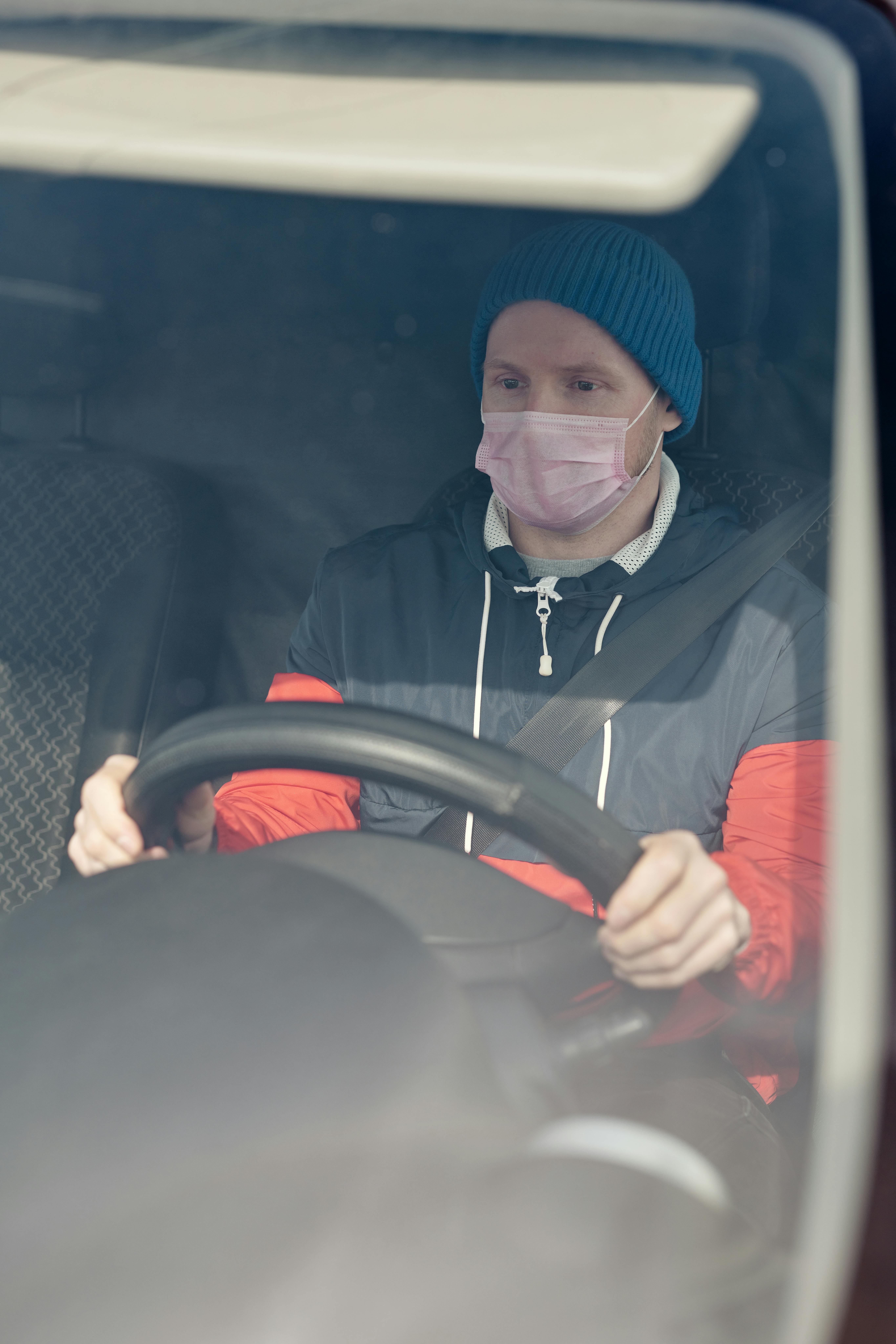 man wearing a face mask driving a vehicle