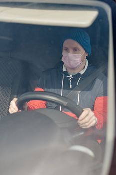 新型冠状病毒肺炎大流行期间，一名男子戴着口罩驾车