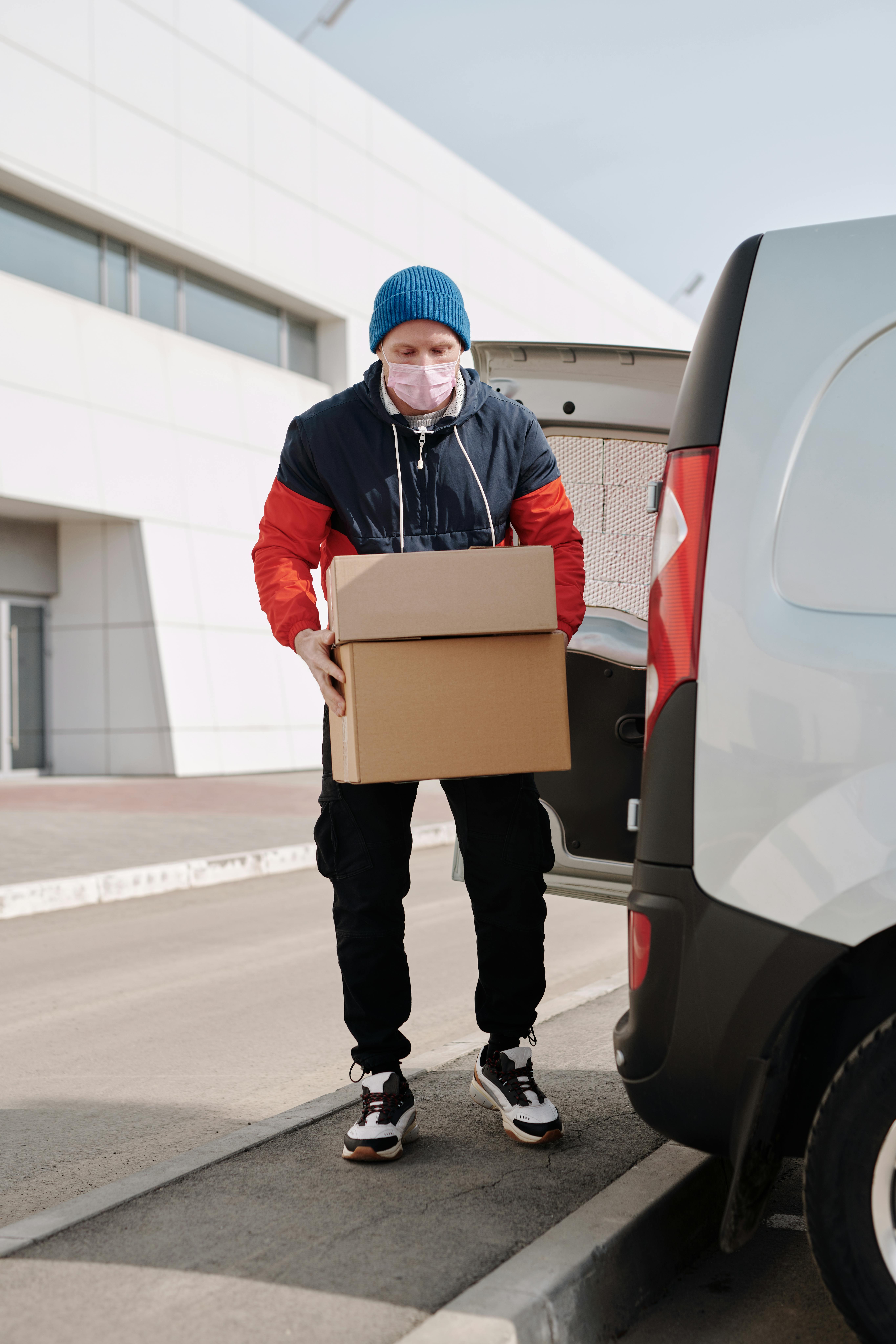 delivery man wearing a face mask carrying boxes