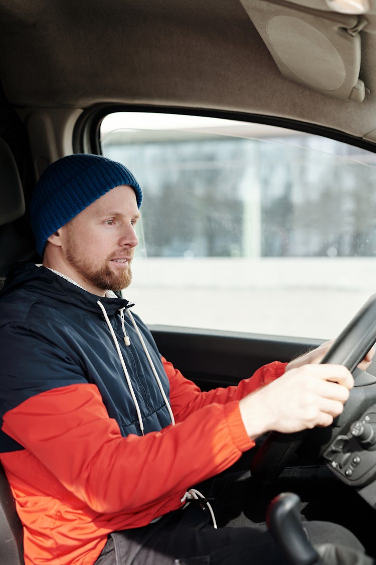 A Bearded Man In A Jacket Driving A Car