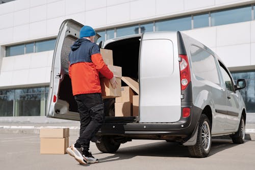 A Man in a Jacket Loading Boxes in a Van