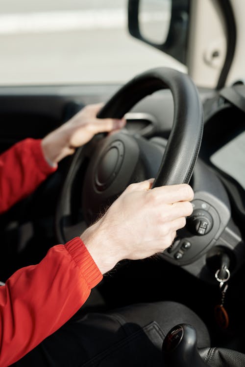 Free A person's hands gripping the steering wheel inside a vehicle, emphasizing safe driving. Stock Photo