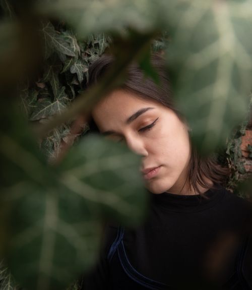 Free A tranquil portrait of a woman with eyes closed amidst vibrant green foliage. Stock Photo