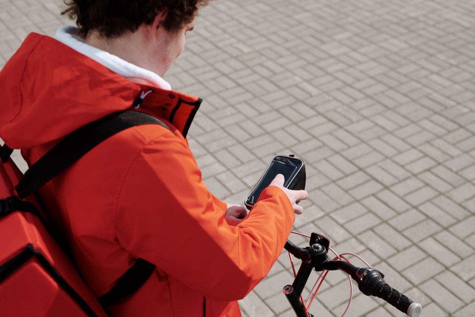Delivery man on a bicycle checking smartphone for directions. Delivery man on a bicycle checking smartphone for directions.