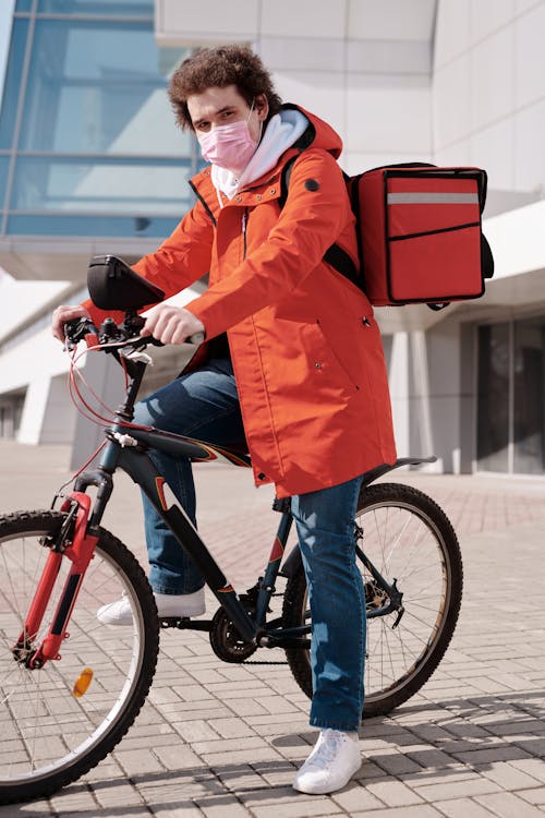 Free Delivery Man Wearing a Face Mask and Riding a Bicycle Stock Photo
