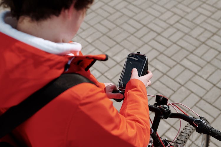 A Person Using A Smartphone On The Bicycle