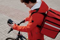 Man Wearing Thermal Bag Holding a Bicycle