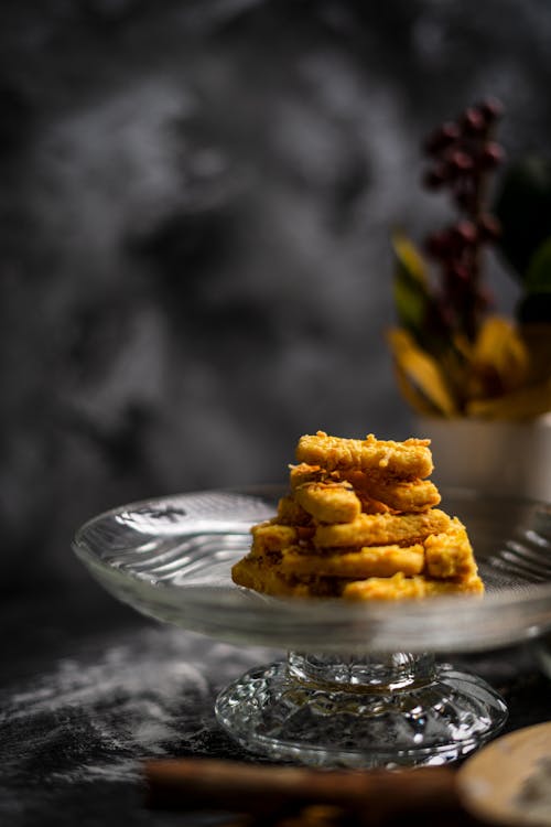 Glass vase with homemade yummy sweet desserts placed on floury table in kitchen