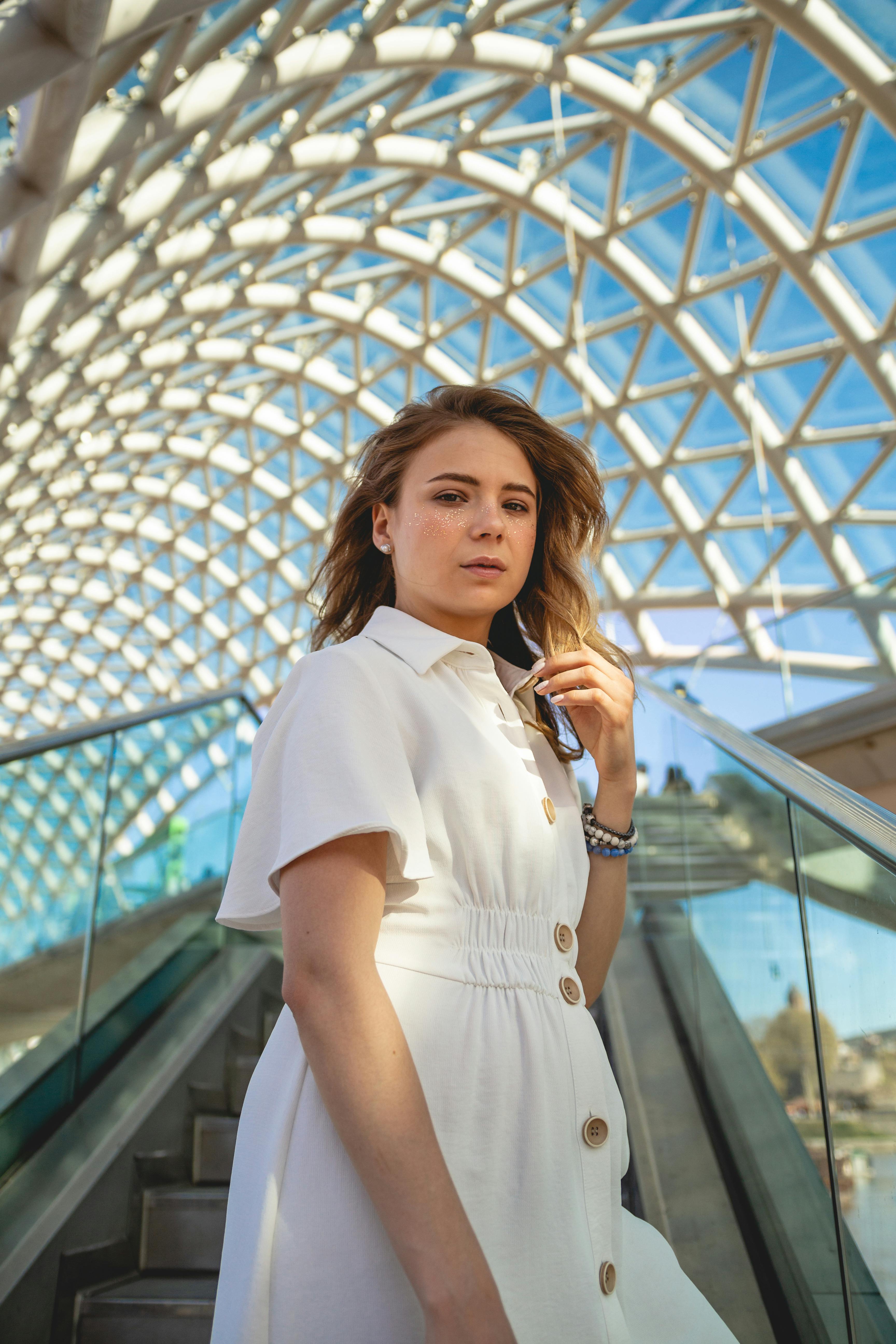 woman in white button up shirt standing near glass handrail