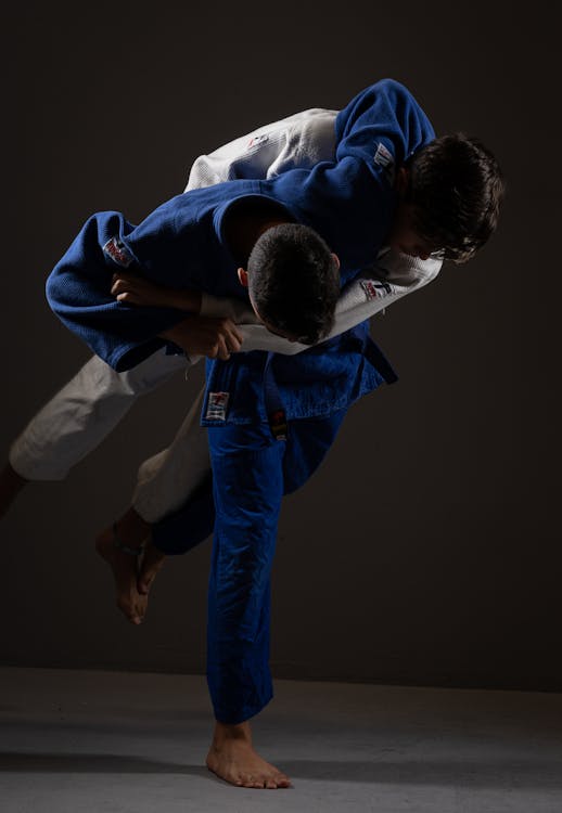 Anonymous strong sportsmen practicing judo on floor