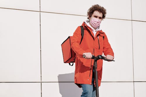 Delivery Man Wearing a Face Mask and Riding a Scooter