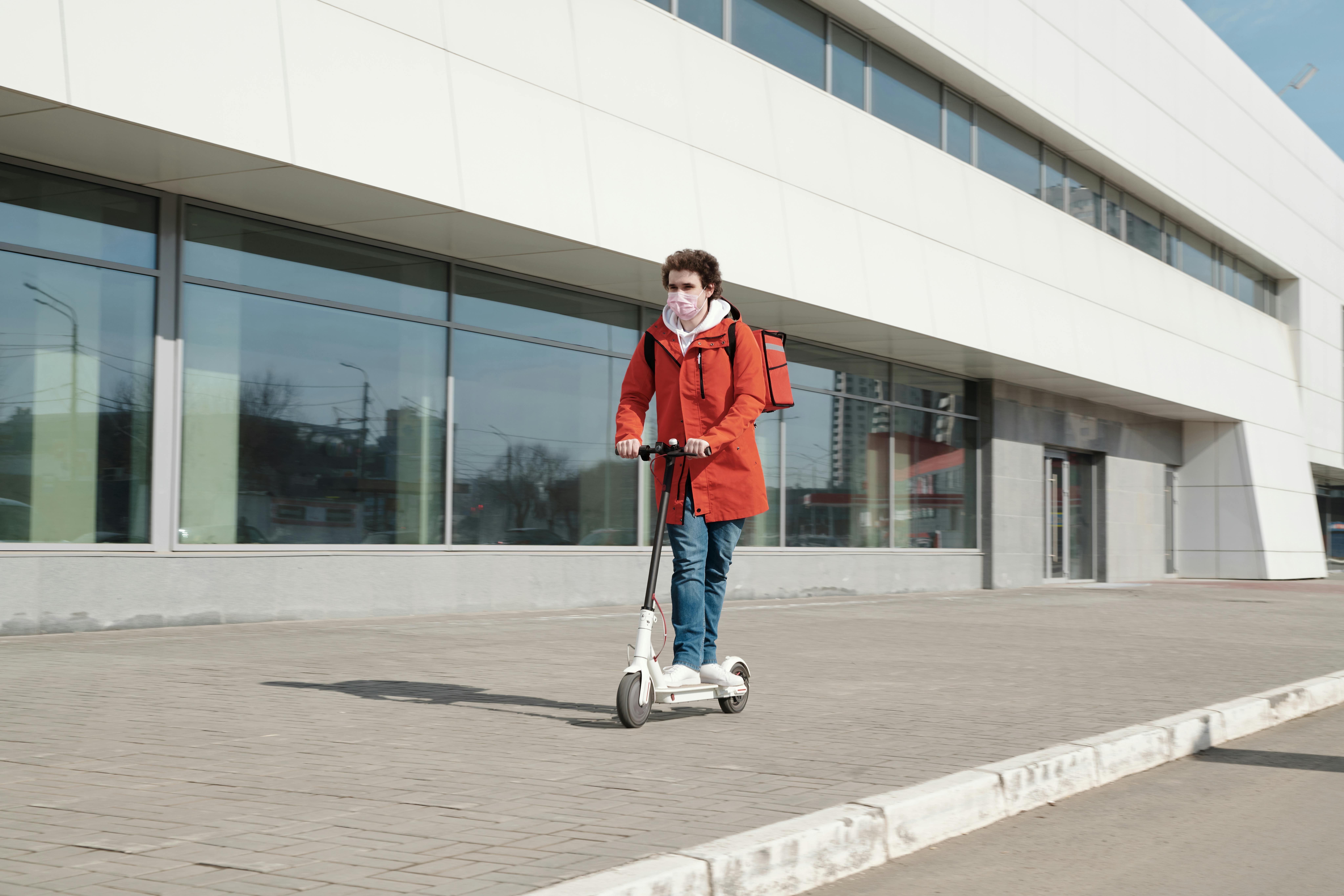 delivery man wearing a face mask and riding a scooter