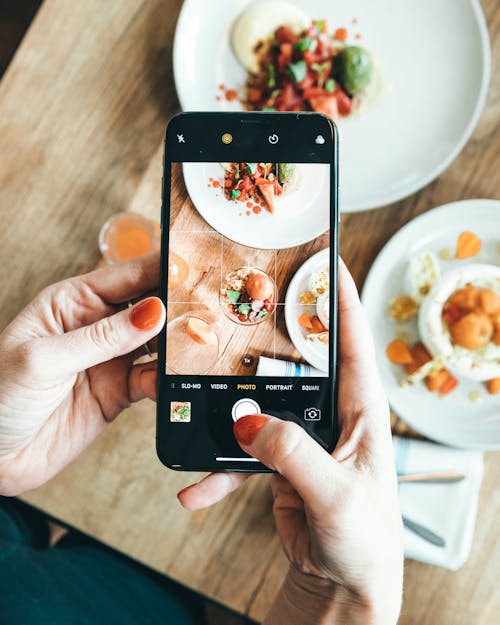 A Person Holding Black Mobile Phone Taking Photo of Food