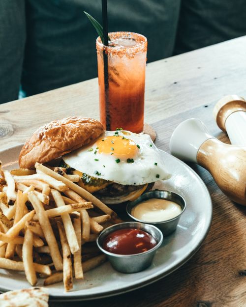 Free Mouthwatering burger with fried egg served with fries and sauce, perfect for lunch or dinner. Stock Photo