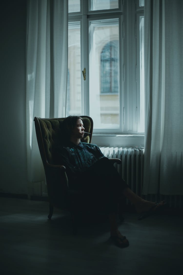 Pensive Person Resting In Armchair In Dark Living Room