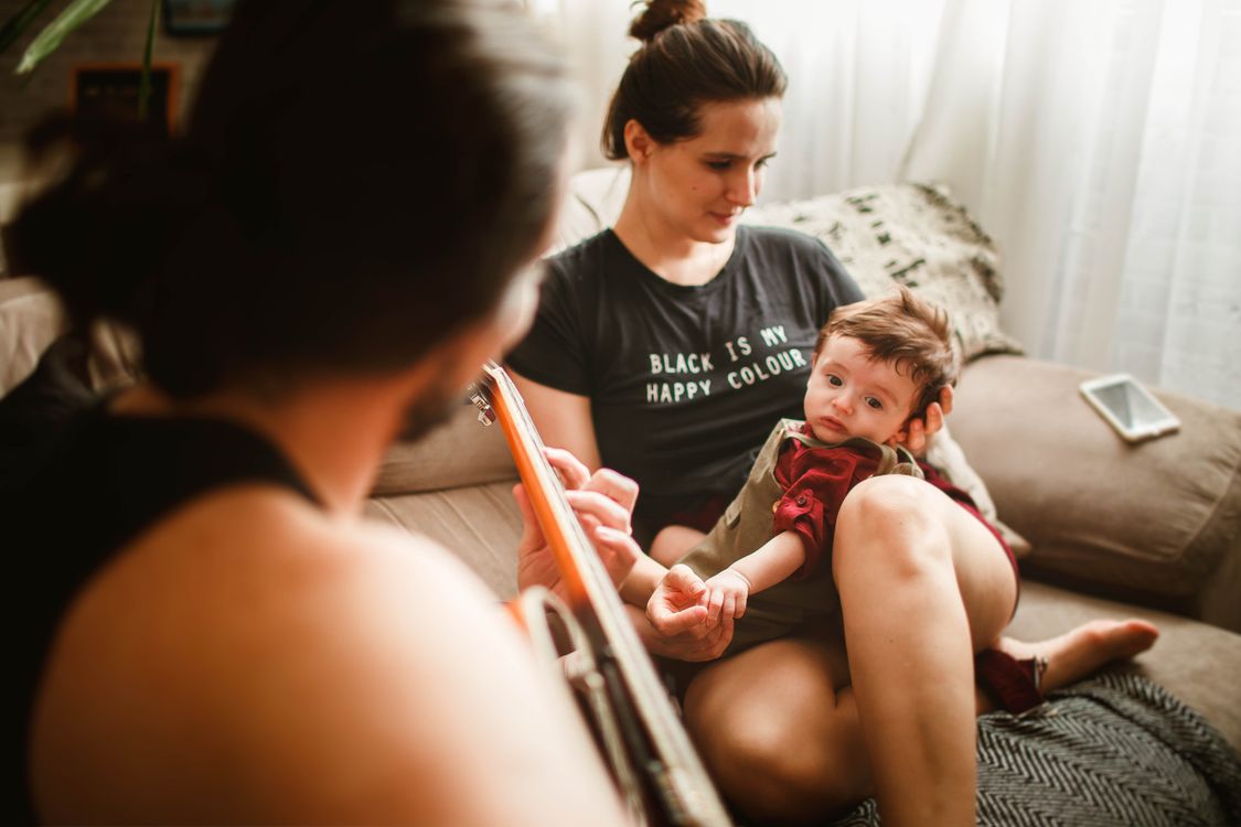 Free Ayah Anonim Bermain Gitar Di Sofa Untuk Bayi Dan Istrinya Stock Photo
