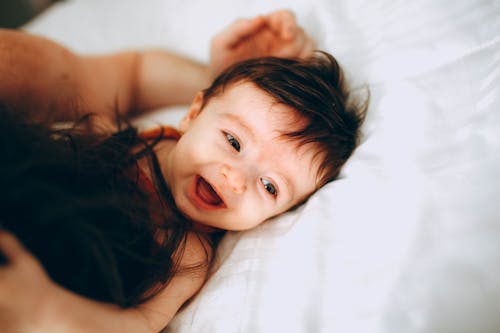 Free Happy infant playing with parent in bed Stock Photo