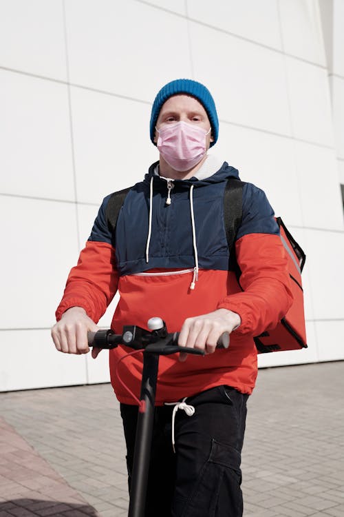 Man Wearing a Face Mask Riding a Scooter