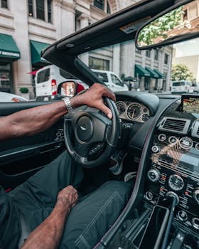 Close-up of a man driving a luxury convertible in a bustling urban area.