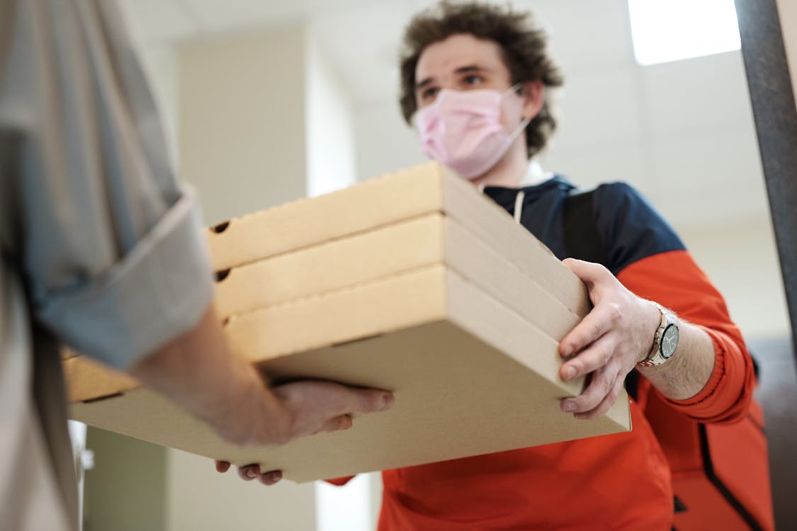 Free Man Wearing a Face Mask Delivering Pizza Stock Photo