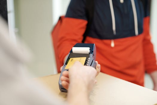 Close-up view of a contactless payment transaction using a credit card on a terminal device.