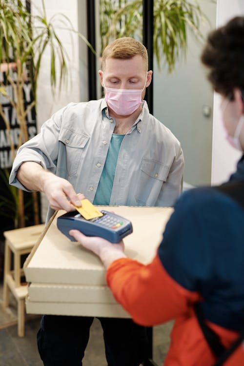 Man Wearing a Face Mask Paying for Pizza Delivery