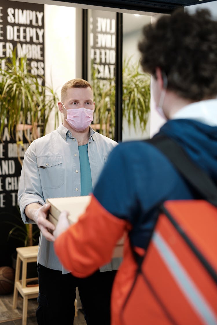 Man With A Face Mask Receiving A Pizza Delivery